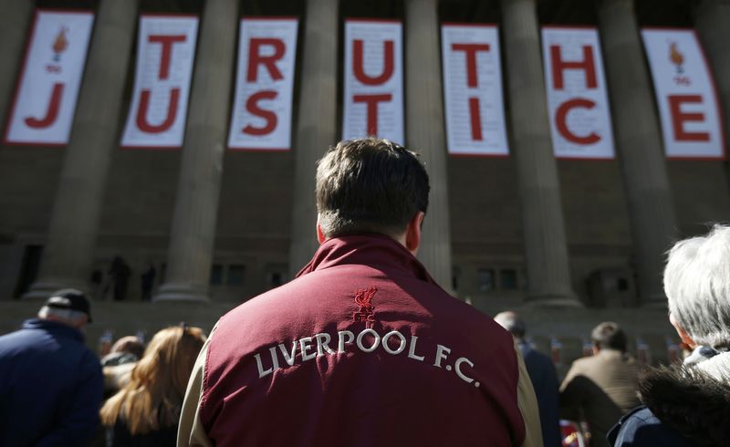© Reuters. People look at floral tributes in memory of the victims of the Hillsborough disaster at St Georges Hall in Liverpool, northern England.