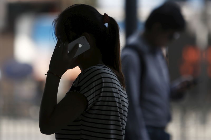 © Reuters. File photo of a woman speaking on her iPhone as she walks on a busy street in downtown Shanghai