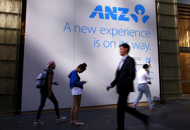 © Reuters. Pedestrians walk past a woman as she looks at her iPhone in front of a sign announcing a new branch of the Australia and New Zealand Banking Group Ltd in central Sydney, Australia