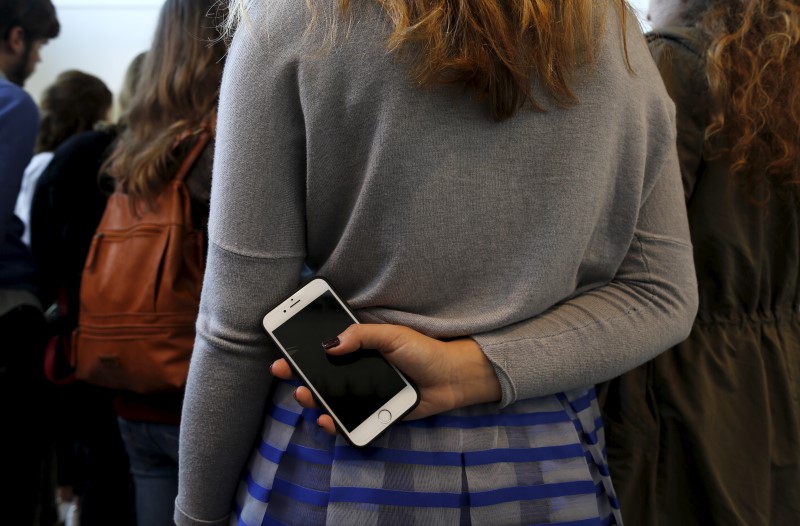 © Reuters. A visitor holds a cell phone as she visits the ARTS/artsevilla International Contemporary Art Fair in the Andalusian capital of Seville