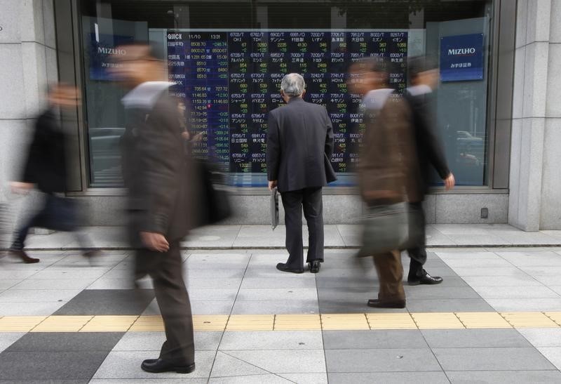 © Reuters. Man looks at an electronic board displaying stock prices outside a brokerage in Tokyo