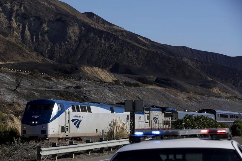 © Reuters. Passengers take pictures from an northbound Amtrak train in the aftermath of a wildfire in the Solimar Beach area of Ventura County, California