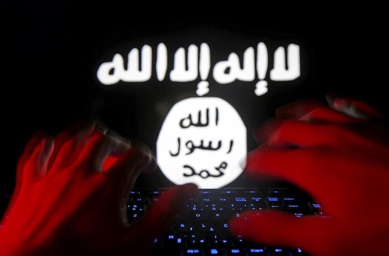 © Reuters. Picture illustration taken in Zenica shows man typing on a keyboard in front of a computer screen on which an Islamic State flag is displayed