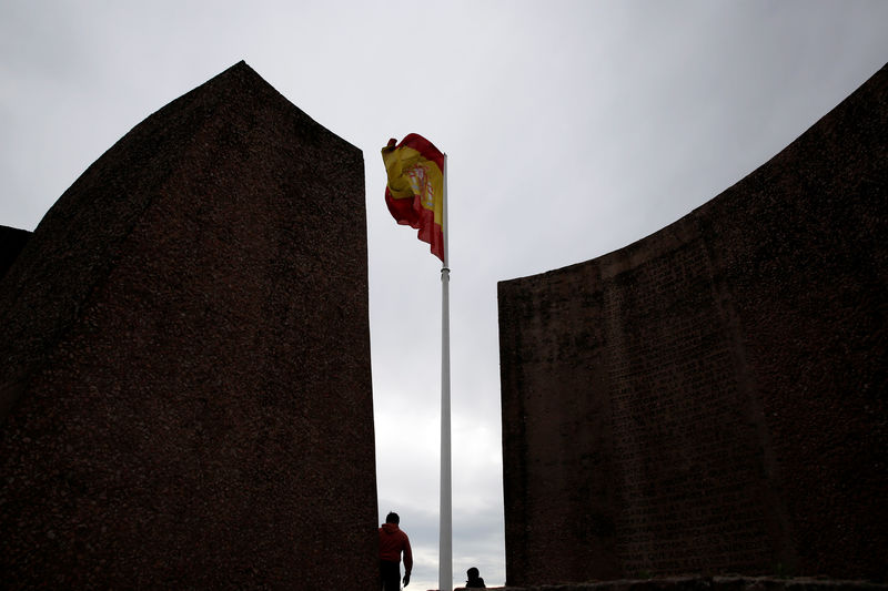 © Reuters. People stand near a Spanish flag in Plaza Colon in Madrid