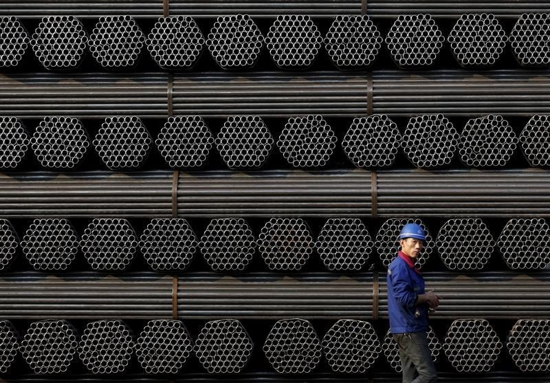 © Reuters. File photo of a worker walking past a pile of steel pipe products at the yard of Youfa steel pipe plant in Tangshan in China's Hebei Province