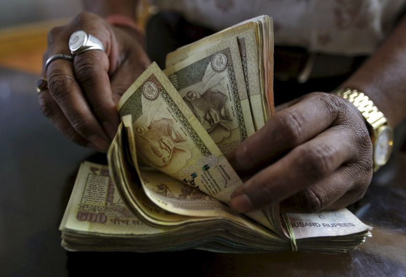 © Reuters. File photo of a money lender counting Indian rupee currency notes at his shop in Ahmedabad