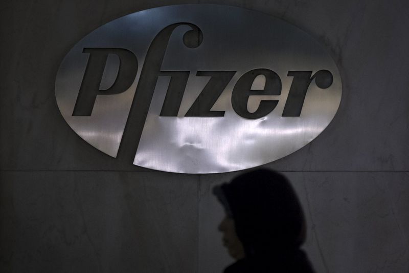 © Reuters. A woman walks past a Pfizer logo on their building in the Manhattan borough of New York