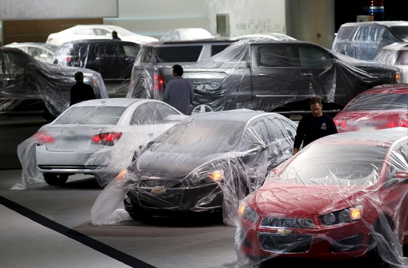 © Reuters. Vehicles are covered with protective wrap as workers prepare the General Motors automakers display ahead of the media preview of the North American International Auto Show in Detroit