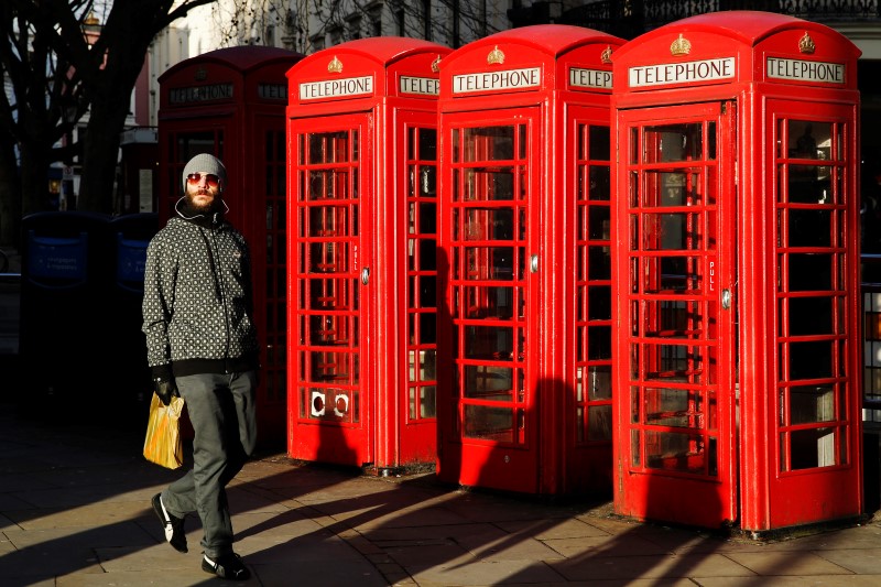© Reuters. A man passes a row of traditional telephone boxes in London