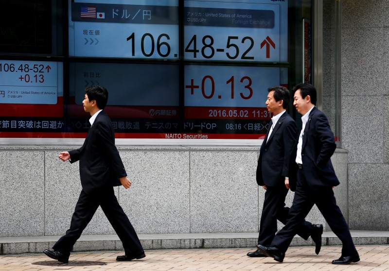 © Reuters. Businessmen walk past a display showing the dollar to yen exchange rate in Tokyo, Japan