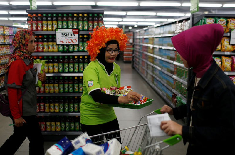 © Reuters. A sales promoter offers a food sample to a customer at Foodmart Fresh supermarket in Jakarta