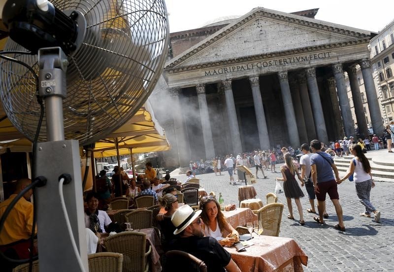 © Reuters. People sit in a restaurant as fans disperse mist in front of Pantheon during a hot summer day in in Rome