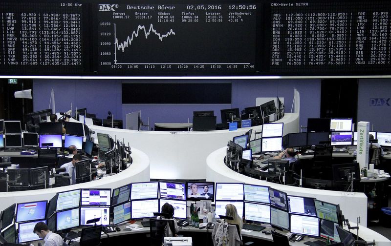 © Reuters. Traders work at their desks in front of the German share price index, DAX board, at the stock exchange in Frankfurt