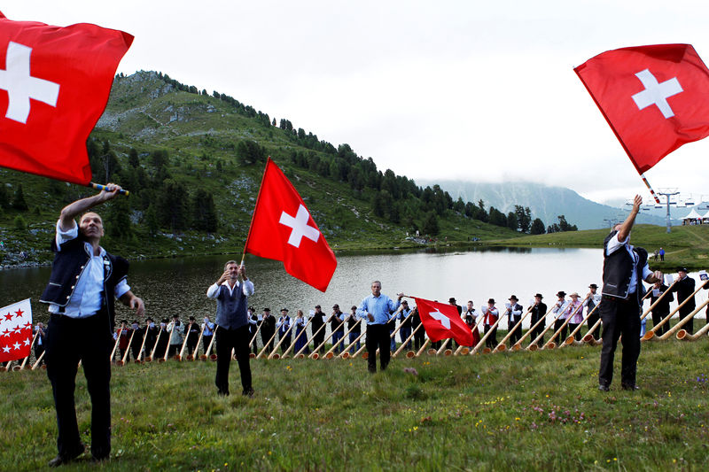 © Reuters. File photo of Alphorn blowers and flag throwers performing an ensemble piece on the last day of the International Alphorn Festival on Lac de Tracouet near the village of Nendaz