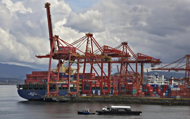 © Reuters. A tugboat pulling a transport truck on a barge crosses the harbour beside the container port in Vancouver