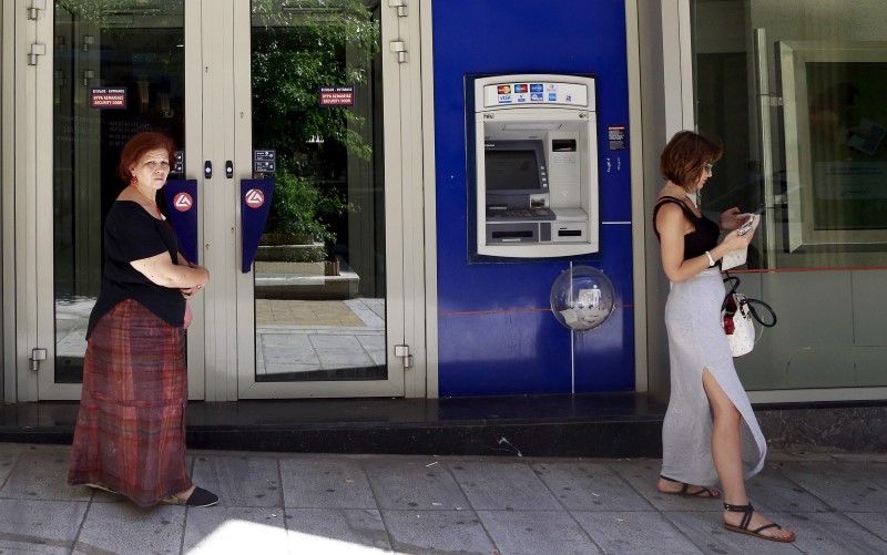 © Reuters. People walk near an ATM machine in central Athens, Greece 