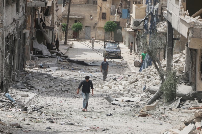 © Reuters. People walk on the rubble of damaged buildings after an airstrike in the rebel held area of Aleppo's Baedeen district