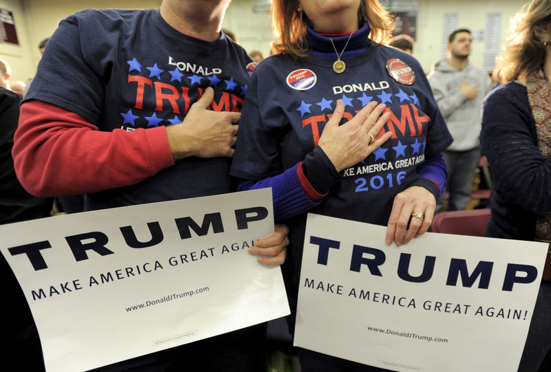 © Reuters. Supporters of U.S. Republican presidential candidate Donald Trump hold their hands to their chest as the national anthem is played at a campaign rally in Concord