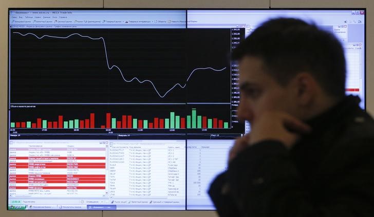 © Reuters. Человек идет мимо дисплея Московско фондовой биржи, показывающего данные об акциях 