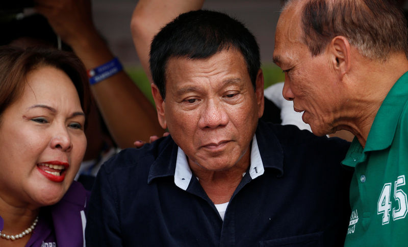 © Reuters. Presidential candidate Rodrigo "Digong" Duterte (C) listens as Senatorial candidates Dionisio Santiago (R) and Sandra Cam talk to him during election campaigning in Malabon, Metro Manila