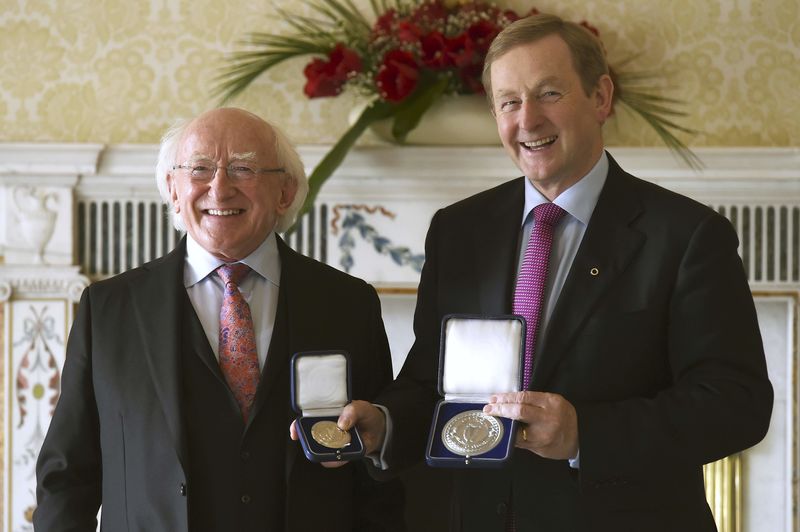 © Reuters. President Michael D. Higgins poses as Irish Prime Minister Enda Kenny holds the holds the Seal of Taoiseach and the Seal of Government to office, in Dublin