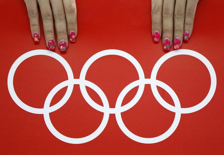 © Reuters. A volunteer's nails are seen beside the Olympic rings during the women's 5,000 metres speed skating race at the Adler Arena in the Sochi 2014 Winter Olympic Games