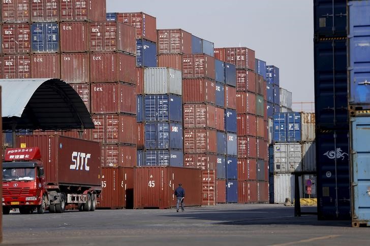 © Reuters. A man walks past container boxes at a port in Shanghai