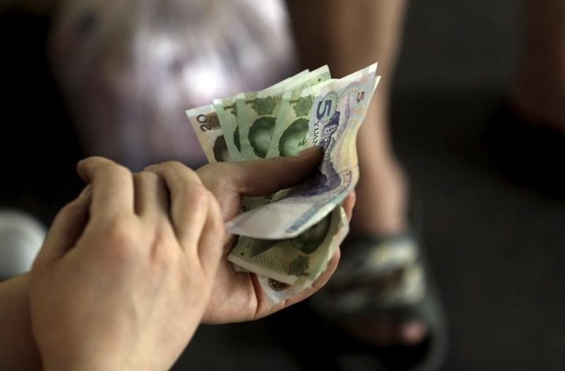 © Reuters. A customer holds Chinese Yuan notes as she pays for pork at a market in Beijing