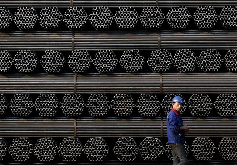 © Reuters. File photo of a worker walking past a pile of steel pipe products at the yard of Youfa steel pipe plant in Tangshan in China's Hebei Province