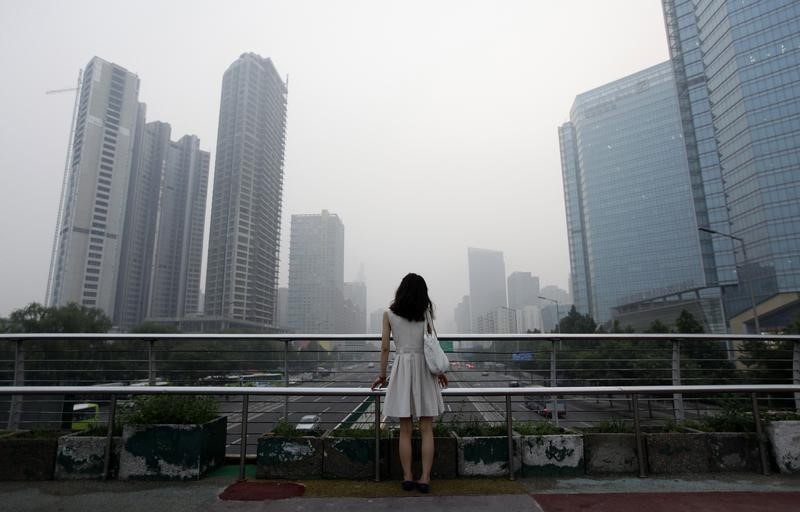 © Reuters. File picture of a woman standing on an overhead bridge near the construction site of  "Kaisa Plaza", then named "Changan No. 8", on a hazy day in Beijing's central business district