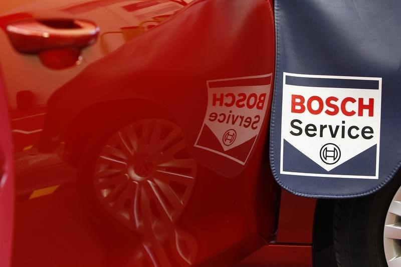 © Reuters. Service sign is reflected in car door while product expert for diagnostics equipment of German auto parts supplier Robert Bosch analyses a car in garage in Plochingen