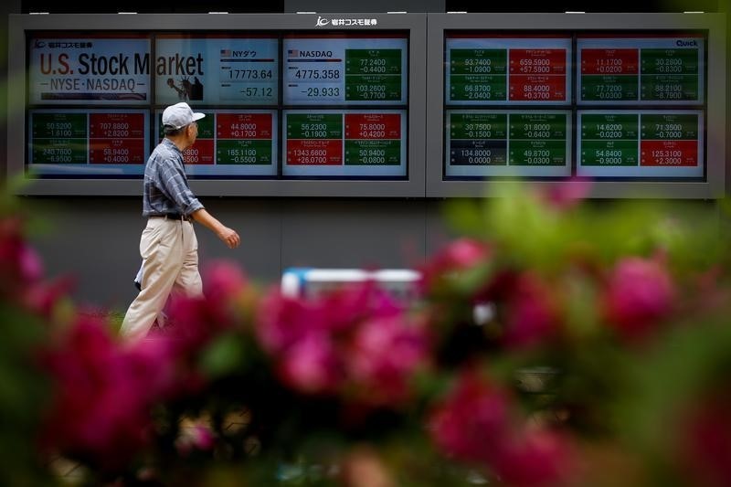 © Reuters. A man walks past a display of market indices in Tokyo