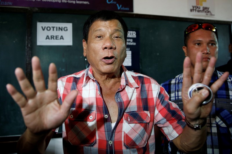 © Reuters. Presidential candidate Rodrigo "Digong" Duterte talks to the media before casting his vote at a polling precinct for national elections at Daniel Aguinaldo National High School in Davao