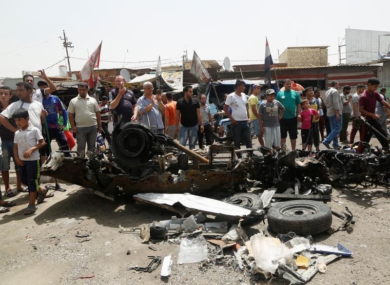 © Reuters. Pessoas perto de carro-bomba que explosiu em Bagdá 