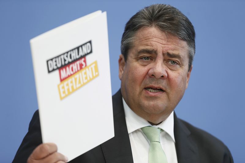 © Reuters. German Economy Minister Gabriel holds a report reading 'Germany does it efficiently' at a news conference in Berlin