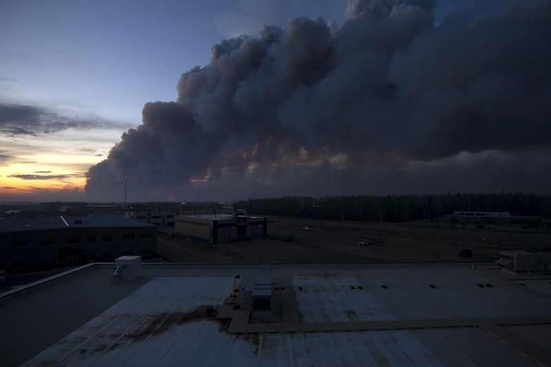 © Reuters. A massive plume of smoke, from a wildfire north of the city, stretches over Fort McMurray Alberta