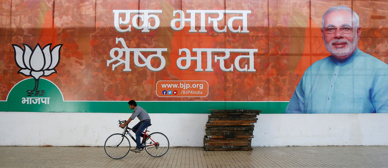 © Reuters. File photo of a worker of BJP riding his bicycle past the party's campaign billboard featuring Prime Minister Modi outside their party headquarters in New Delhi