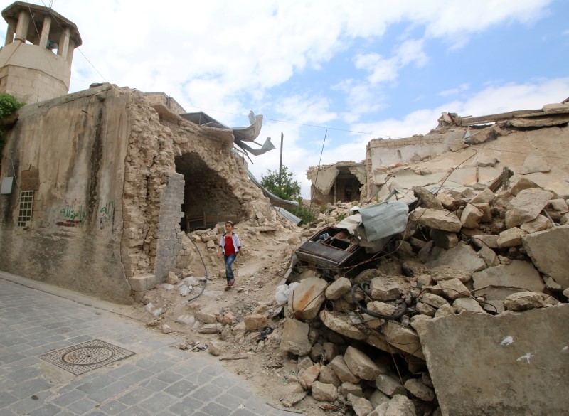 © Reuters. A girl walks near damaged buildings in the rebel held area of Old Aleppo