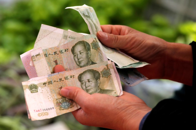 © Reuters. A customer counts Chinese yuan banknotes as she purchases vegetables at a market in Beijing