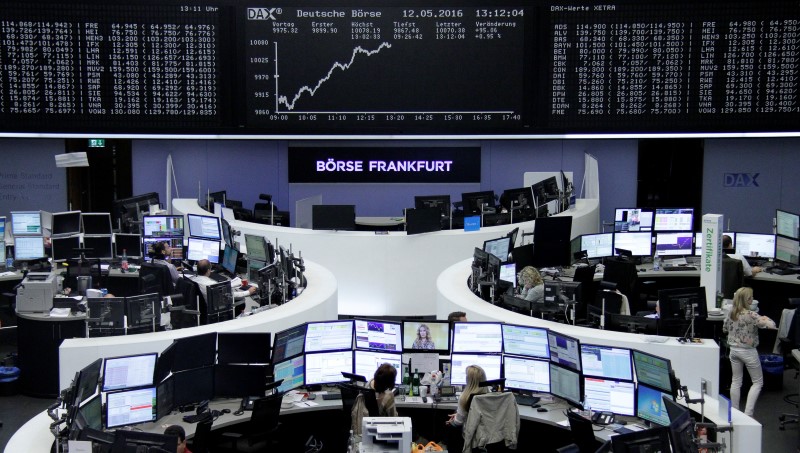 © Reuters. Traders work at their desks in front of the German share price index, DAX board, at the stock exchange in Frankfurt