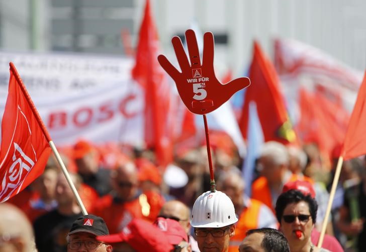 © Reuters. A worker has a sign on helmet with text 'We are for 5%' as steel workers of Germany's IG Metall union protest for higher wages in Cologne