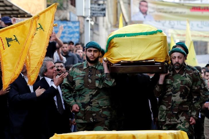 © Reuters. Hezbollah members carry the coffin of top Hezbollah commander Mustafa Badreddine, who was killed in an attack in Syria, as his brother mourns his death during his funeral in Beirut's southern suburbs