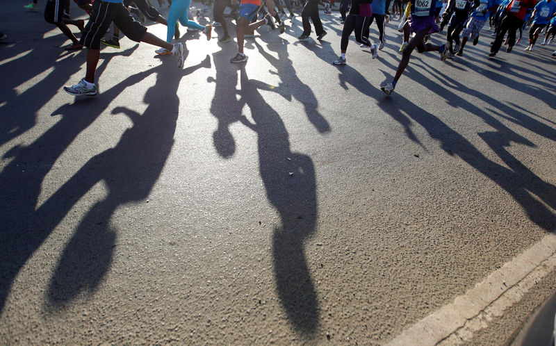 © Reuters. Athletes cast shadows on the ground as they take part in the Nairobi Marathon in Nairobi