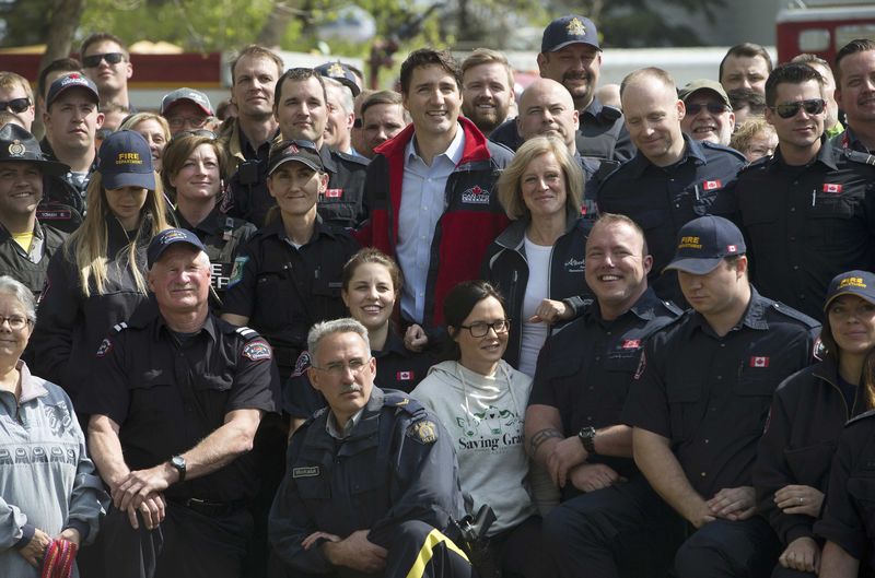 © Reuters.  Prime Minister Justin Trudeau and Alberta Premier pose for a photo with first responders during a visit to Fort McMurray, Alberta, Canada