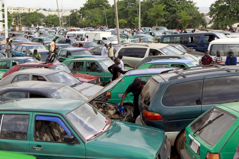 © Reuters. Man works on the engine of his car, as motorists gather at a petrol station of state-owned energy company Nigerian National Petroleum Corporation in Abuja, Nigeria