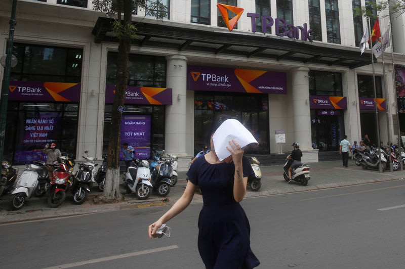 © Reuters. A woman covers her face as she walks out the Vietnamese commercial Tien Phong bank in Hanoi