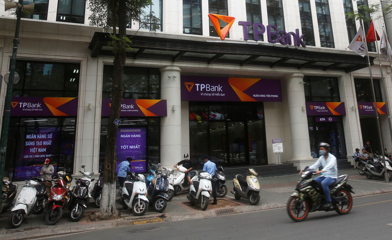 © Reuters. A man rides a motorcycle past the Vietnamese commercial Tien Phong bank in Hanoi 