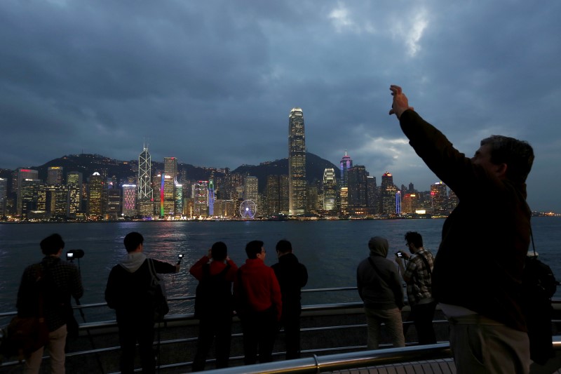 © Reuters. File photo of visitors taking photos on the waterfront of Kowloon peninsula facing Victoria Harbour and Hong Kong island in Hong Kong