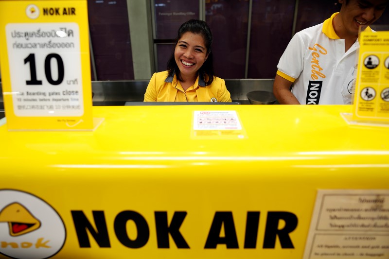 © Reuters. A member of Nok Air's ground staff smiles as passengers check in for their flight at Hat Yai airport