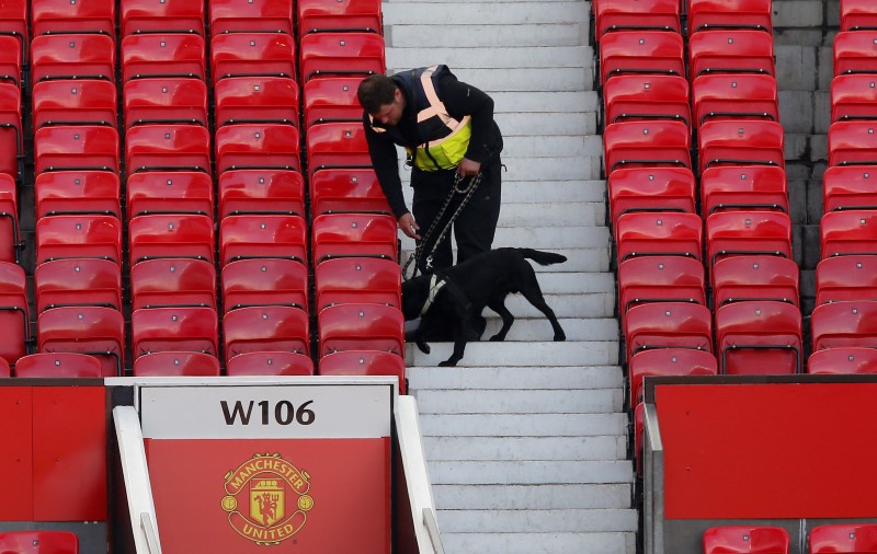 © Reuters. Policial com cão farejador após esvaziamento do estádio Old Trafford, na Inglaterra